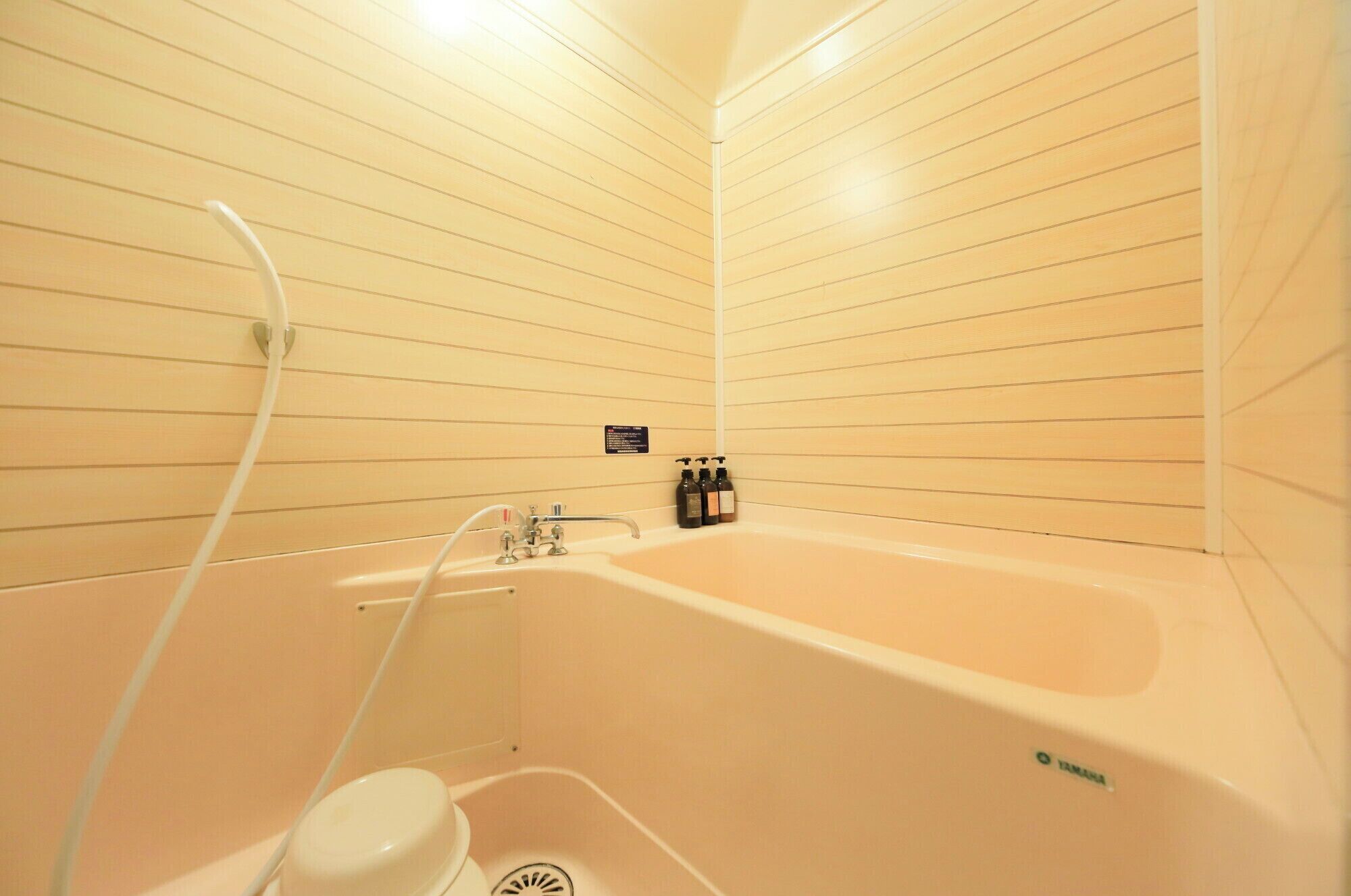 Une salle de bain équipée d’une baignoire, de toilettes et d’une douchette à main. Des articles de toilette sont accrochés au mur.