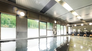 A large indoor swimming pool with clear windows, a tiled floor, and multiple sinks along the wall.