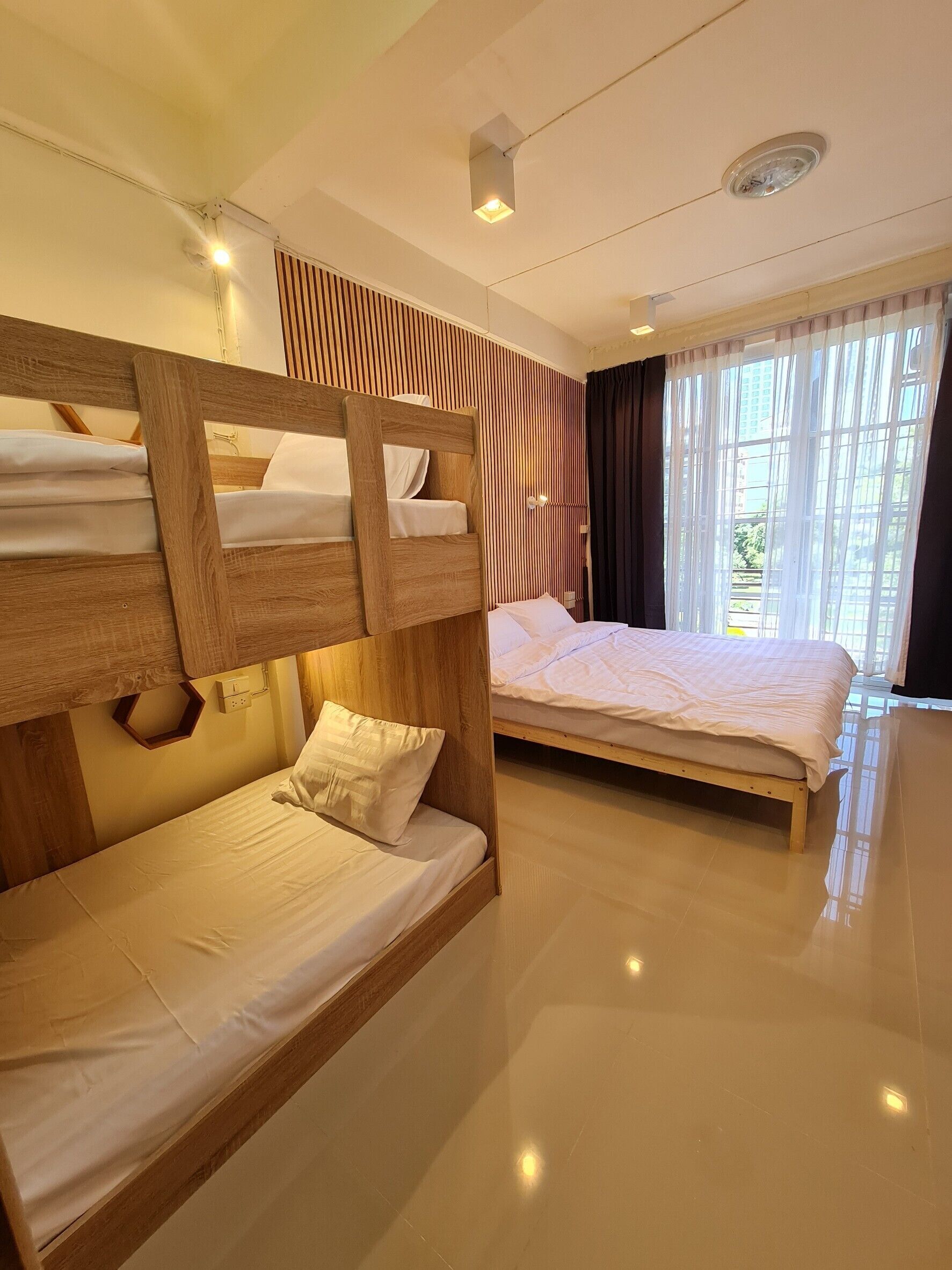 A hotel room with bunk beds, a large window with curtains, and a modern ceiling design.