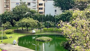 A park with a pond, surrounded by tall residential buildings. - De Chalet (Bangkok)