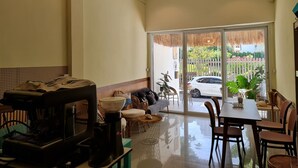 A spacious living area with a coffee machine, sofa, dining table, and chairs. - De Chalet (Bangkok)
