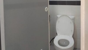 Egy fürdőszoba, amelyben WC, fehér ajtó és csempézett fal található.