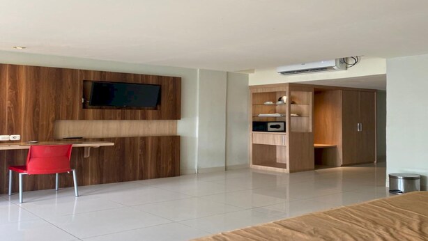 A modern bedroom with a bed, a desk, and a TV mounted on a wooden wall. - OYO 94106 Kitarooms Property (Curug)