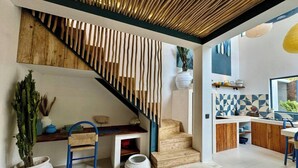 Un interior moderno con una escalera de madera, una zona de cocina y un espacio de comedor.