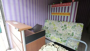 Un espace d’accueil avec un bureau en bois, un banc rembourré et un canapé à motifs.