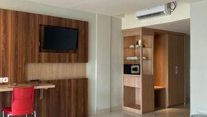 Une chambre à coucher moderne, équipée d’un lit, d’un bureau avec une chaise, d’un téléviseur fixé au mur et d’une armoire.