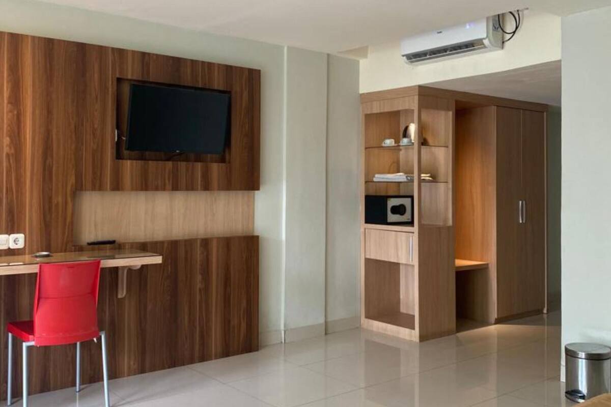 Un dormitorio moderno con cama, escritorio con silla, televisor montado en la pared y armario.