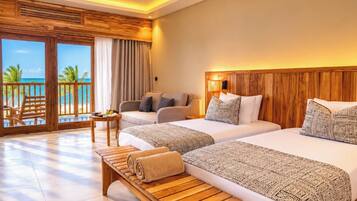 Habitación de hotel con dos camas, un sofá, un banco de madera, una mesita y vista al océano.