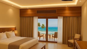 Ein Hotelzimmer mit einem großen Bett, einem Schreibtisch und Blick auf den Strand.