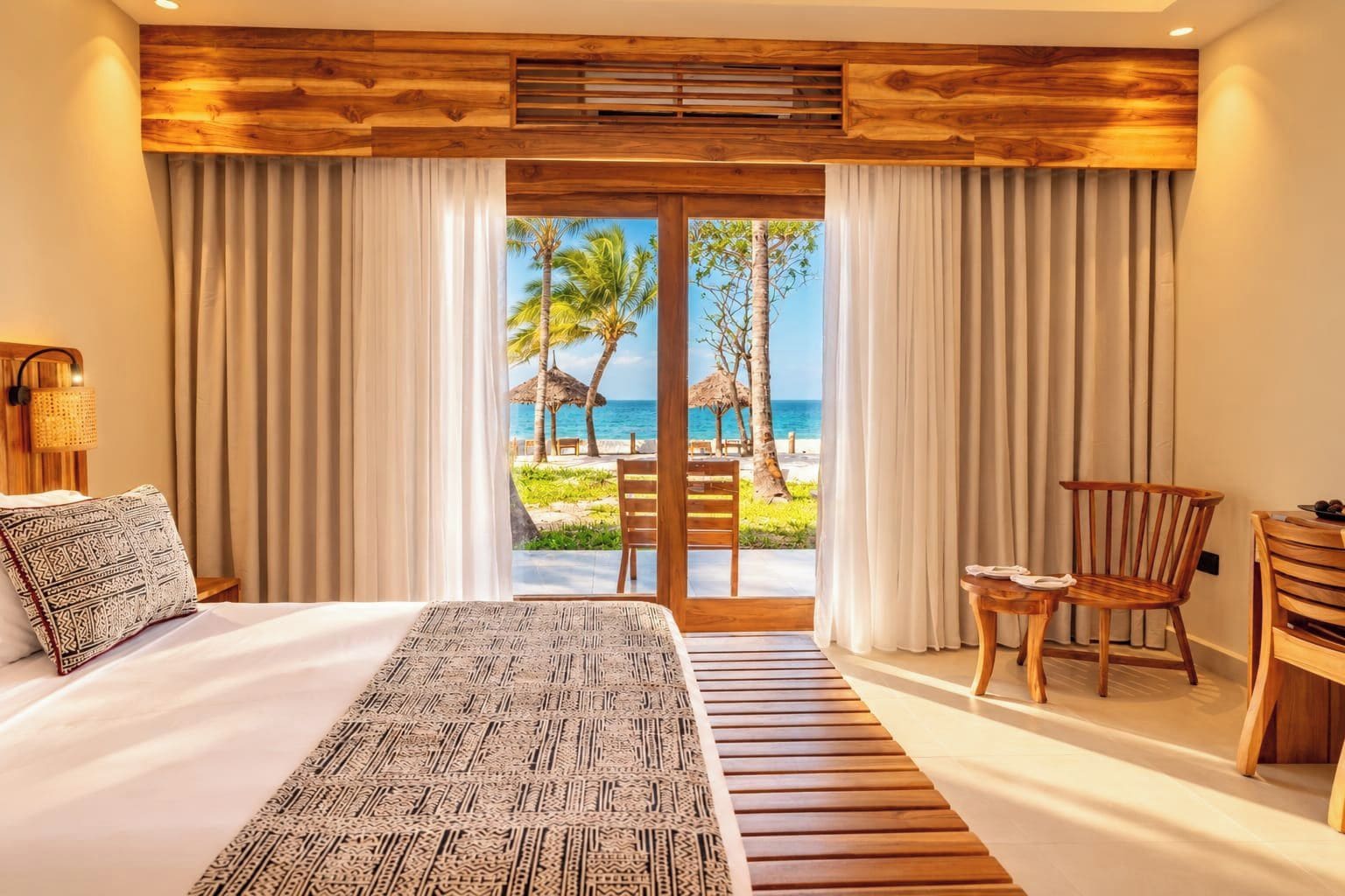 Una habitación de hotel con una cama, una silla, una mesa y vistas a la playa.