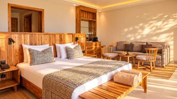 Una habitación de hotel con una cama grande, cabecera de madera, un sofá, una mesita y un banco.