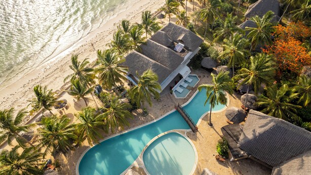 Luftaufnahme eines Resorts mit Swimmingpool, Palmen und Zugang zum Strand.