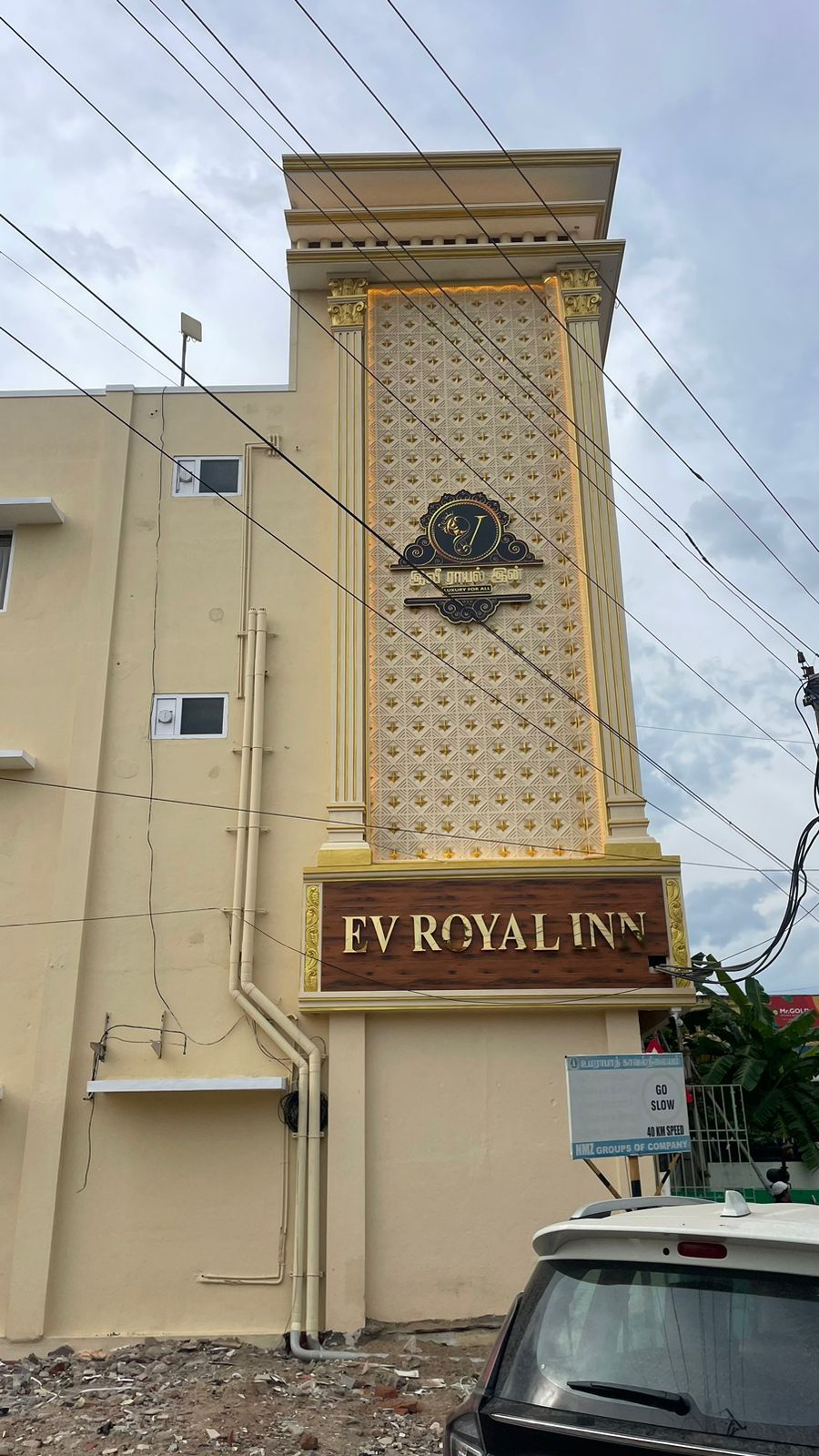 A hotel sign with a prominent emblem and the name 'EV ROYAL INN' displayed on a beige building facade.