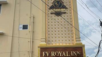 A hotel sign with a prominent emblem and the name 'EV ROYAL INN' displayed on a beige building facade.