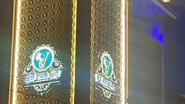 A building with two illuminated vertical panels featuring decorative emblems and text.
