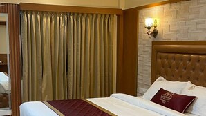Een slaapkamer met een groot bed, een plafondventilator en een stenen muur.