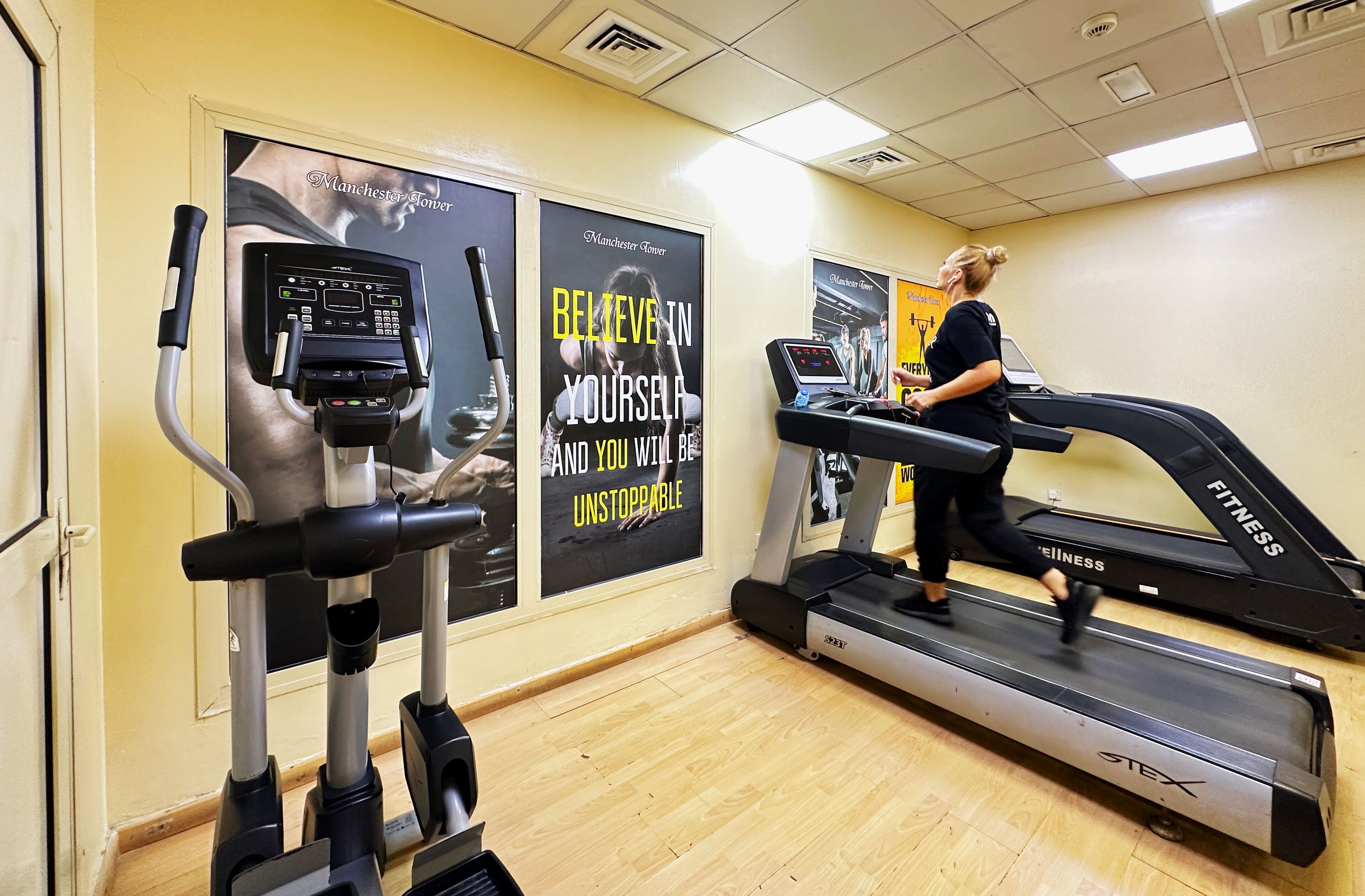 A gym with treadmills, an elliptical machine, and motivational posters on the wall.