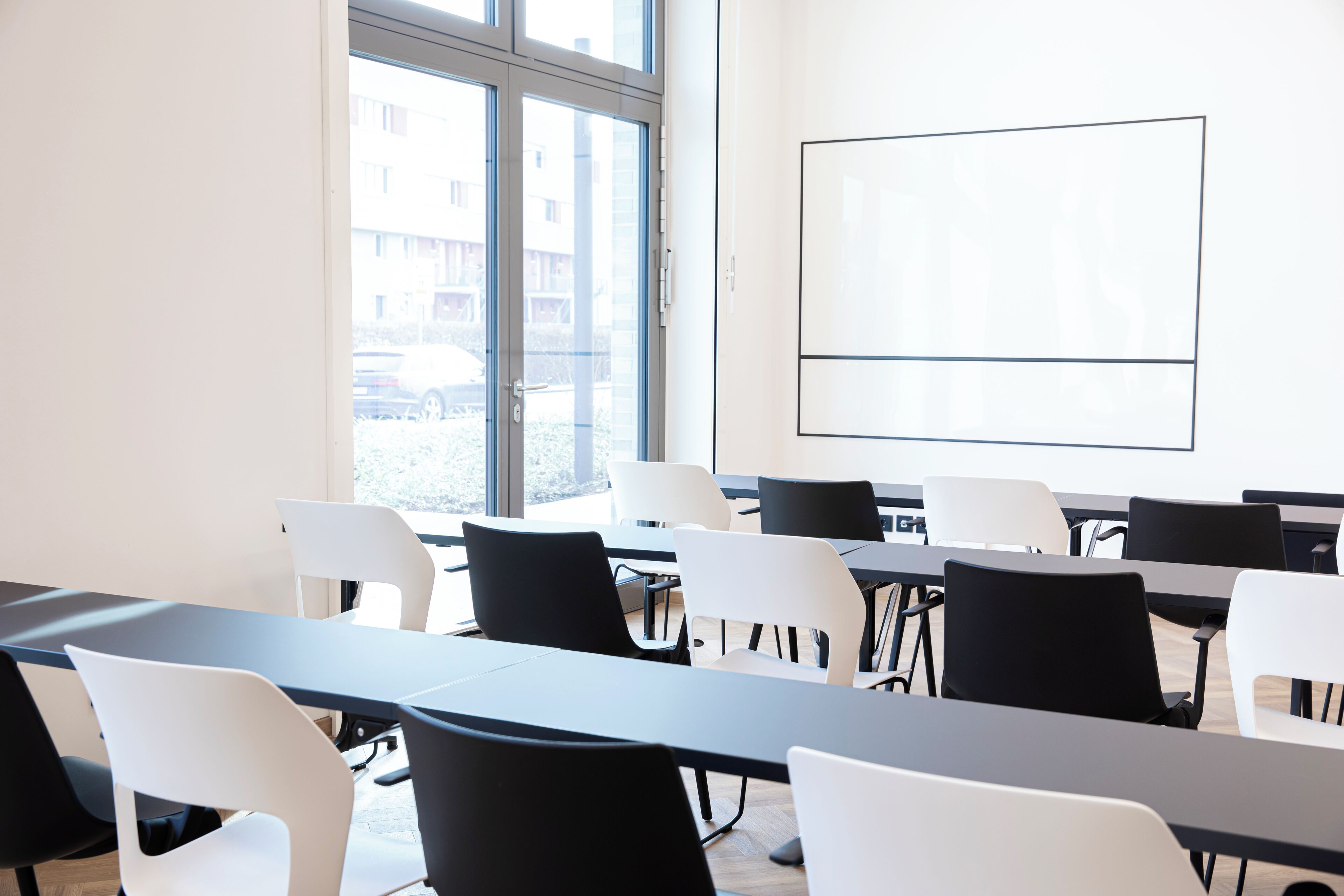 A conference room with tables and chairs, a large window, and a whiteboard.
