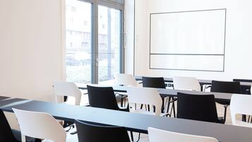 A conference room with tables and chairs, a large window, and a whiteboard.