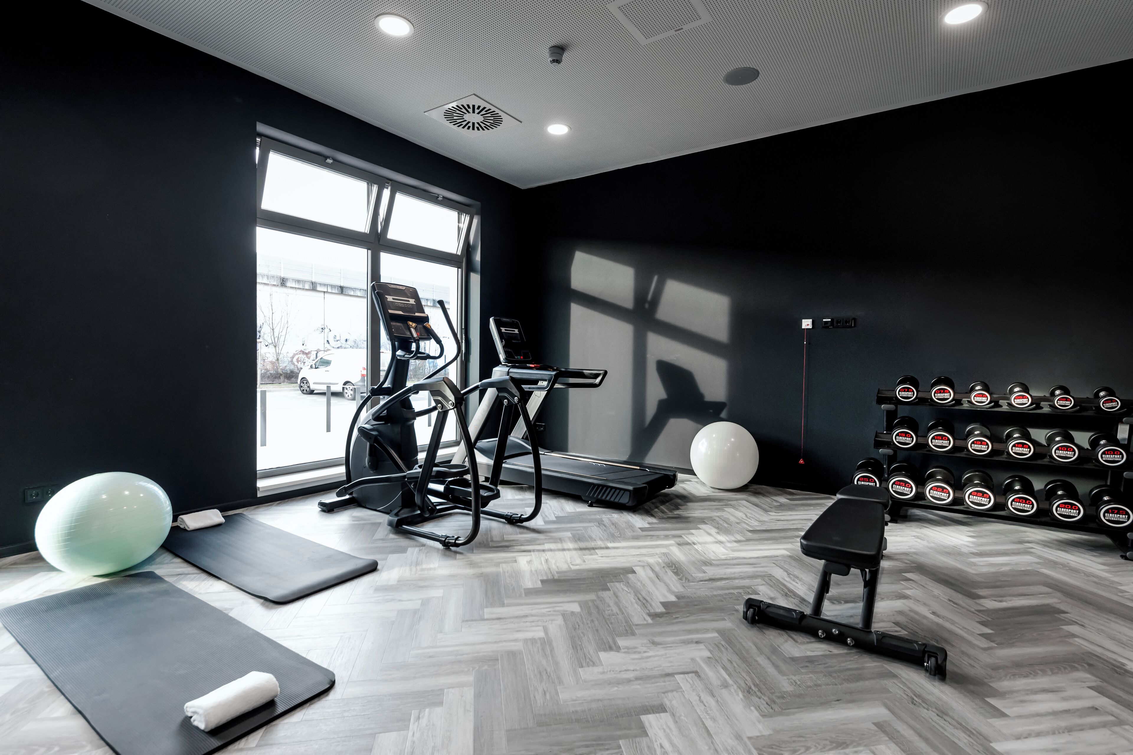 Ein Fitnessraum mit Trainingsgeräten, einer Bank und einem Dumbbell-Gestell.