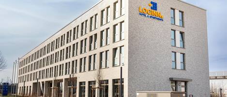 A modern building with a sign reading "LOGINN HOTEL & APARTMENTS".