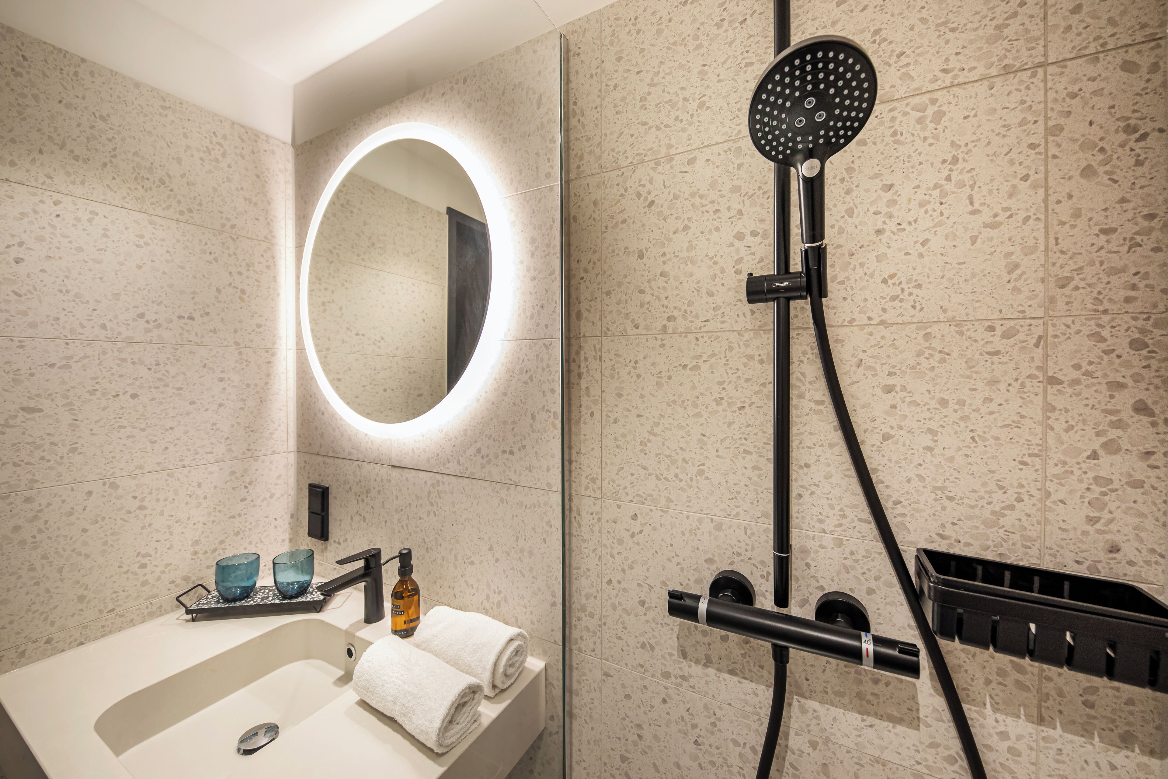 A modern bathroom with a sink, mirror, and shower.