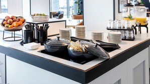 Een ontbijtbuffet met fruit, dranken en bestek.