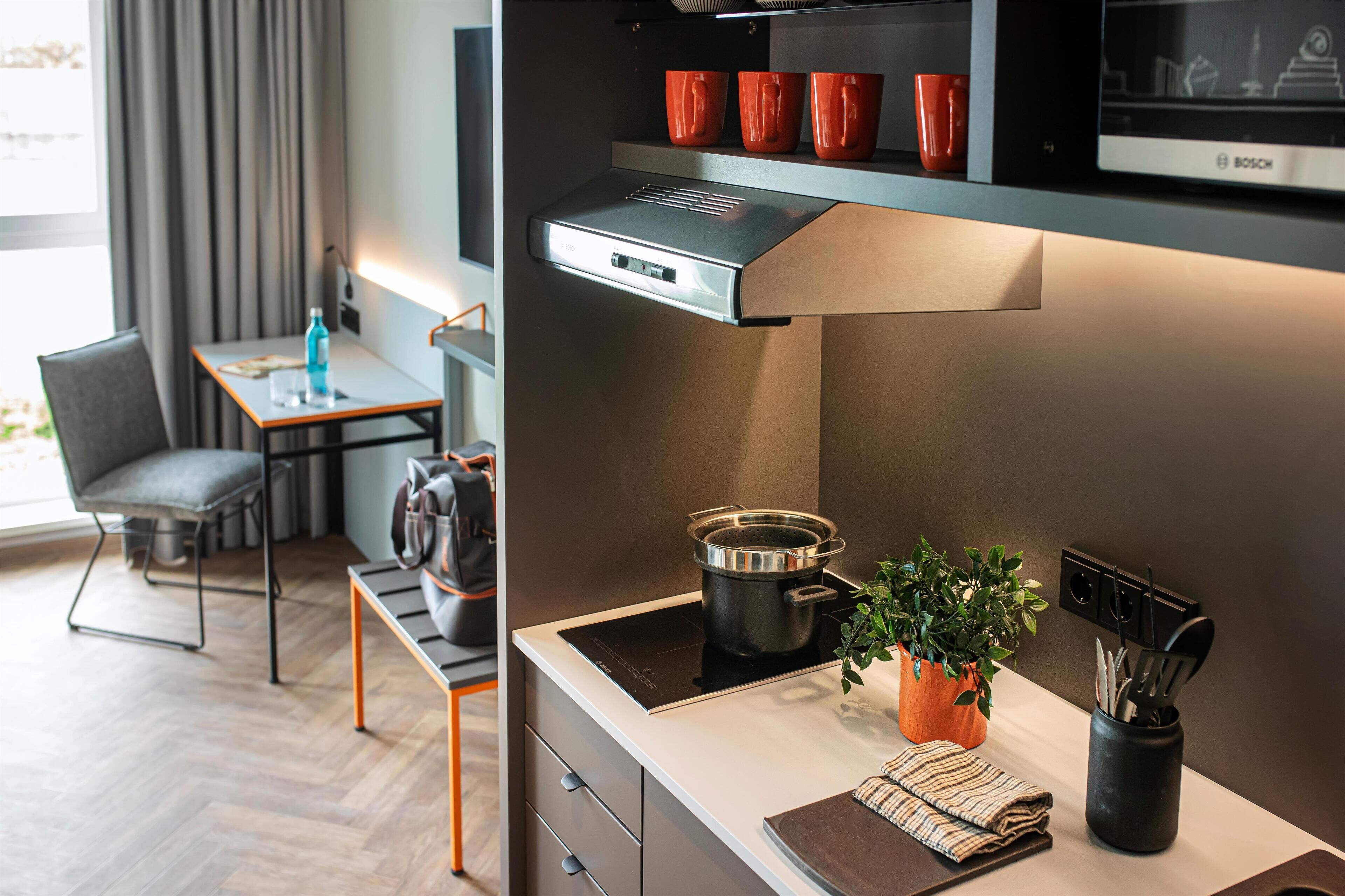 A modern kitchen with a built-in stove, a coffee machine, and a flat-screen TV.
