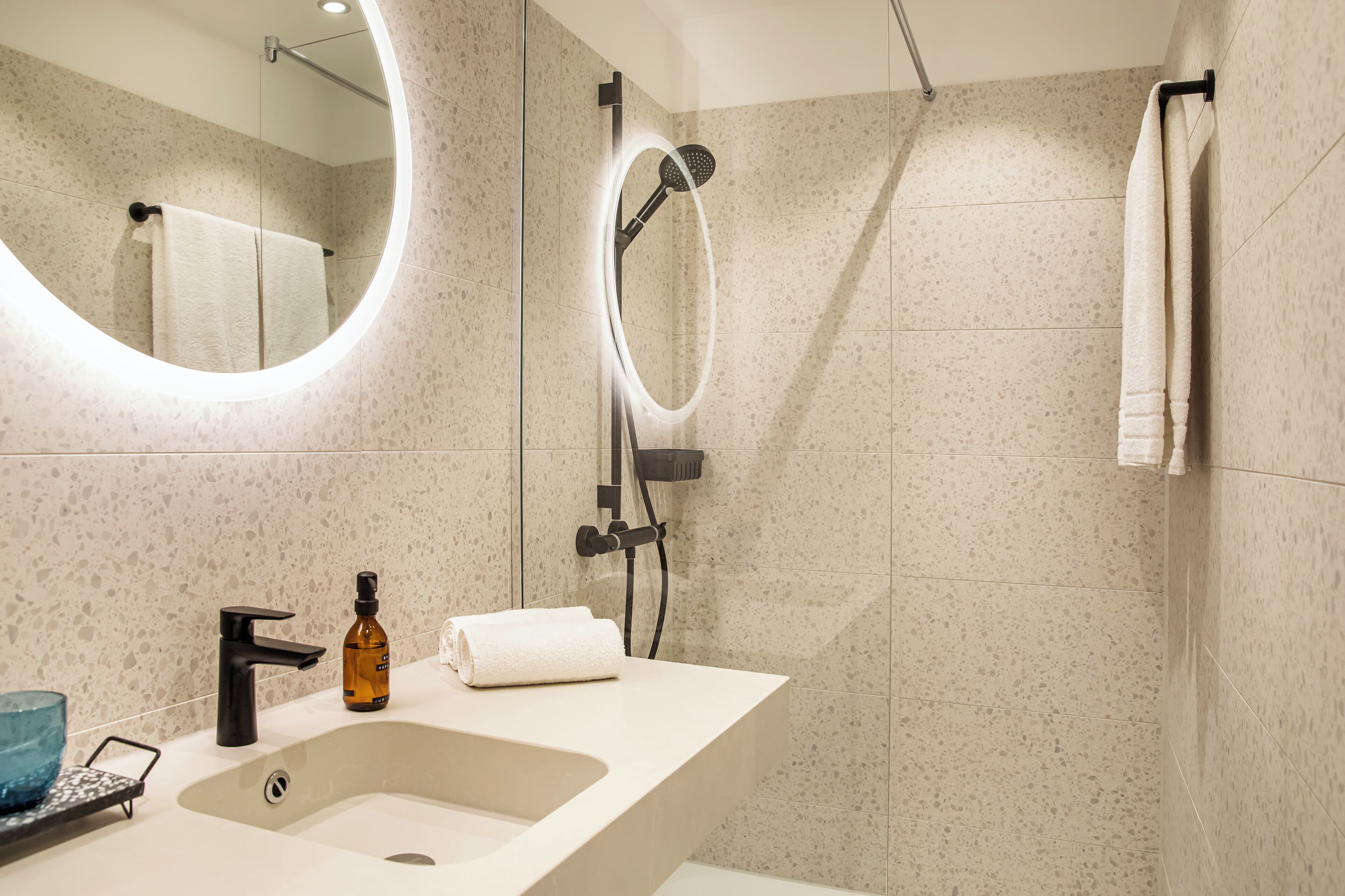 Un baño moderno con lavamanos independiente, ducha de mano y perchero para toallas.