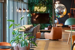 Un moderno espacio de descanso con un letrero de neón que dice 'PLAY', un televisor de pantalla plana grande y asientos cómodos.