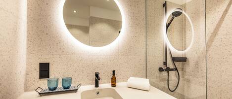 A modern bathroom with a large sink, two blue glass containers, a soap dispenser, and a towel.
