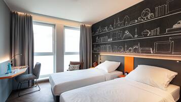 A hotel room with two beds, a desk, a chair, and a large window with curtains.