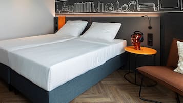 Una habitación de hotel moderna con una cama grande, una mesa redonda pequeña y un sofá.
