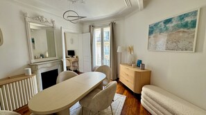 Relax in a classic room with a dining table, comfortable seating area, and a large window offering a view of the outside.