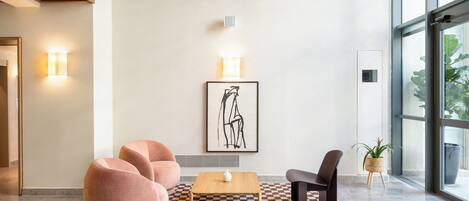 A modern lobby with a checkered rug, a wooden coffee table, a framed artwork, and a potted plant.