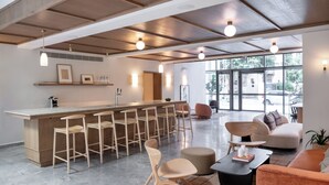 Eine moderne Küche mit Barbereich, Holzbarhocker und einer Sitzecke mit Sofa und Sesseln.