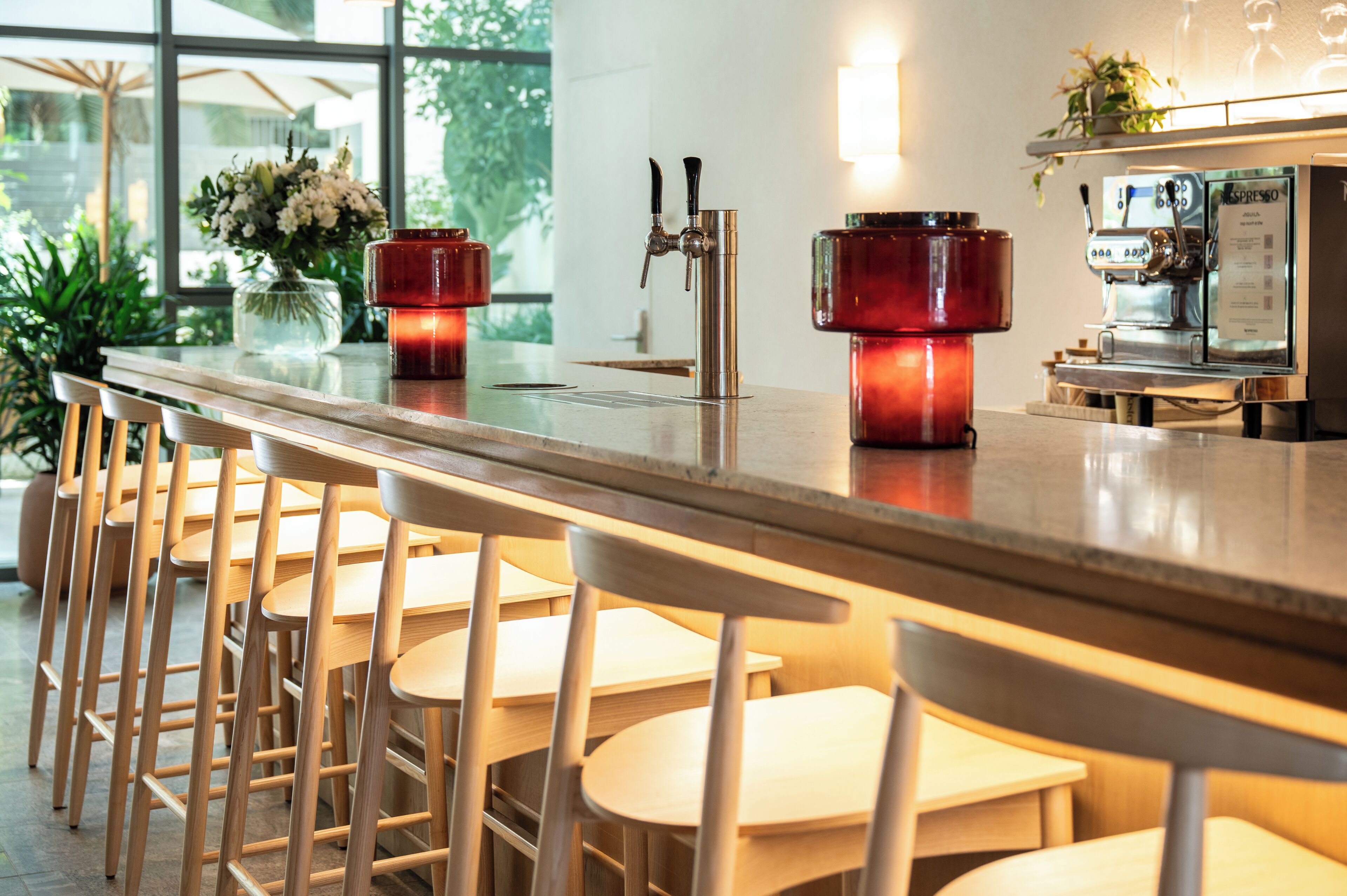 A bar area with a long counter, stools, and a coffee machine.