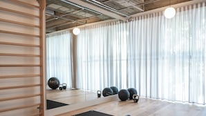 Ein Fitnessraum mit Holzböden, Trainingsmatten, Kettlebells und einem Spiegel.