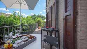 A terrace with a table set for dining, a bench, and a potted plant.