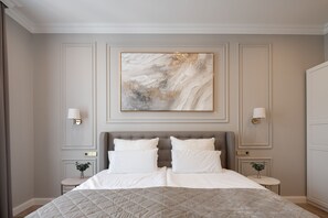 Ein Schlafzimmer mit einem großen Bett, zwei Nachttischen und einem an der Wand hängenden Kunstwerk.