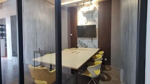 Une salle de conférence dotée d’une grande table, de chaises jaunes et d’un lustre moderne.