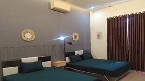 Une chambre d’hôtel avec deux lits, une table de chevet, un climatiseur et une fenêtre avec des rideaux.