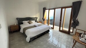 A bedroom with a bed, nightstands, a chair, and a view through a sliding glass door. - Zee House (Canggu)