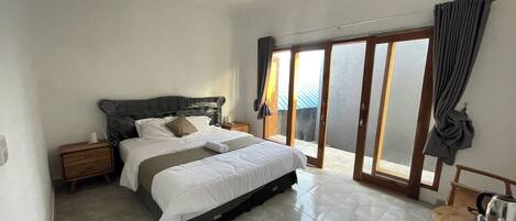 A bedroom with a bed, nightstands, a chair, and a view through a sliding glass door.