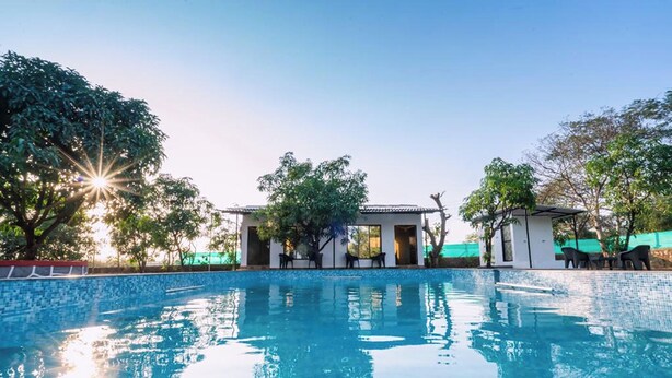 Una piscina con acqua cristallina, circondata da alberi e da un edificio con tetto in tegole.