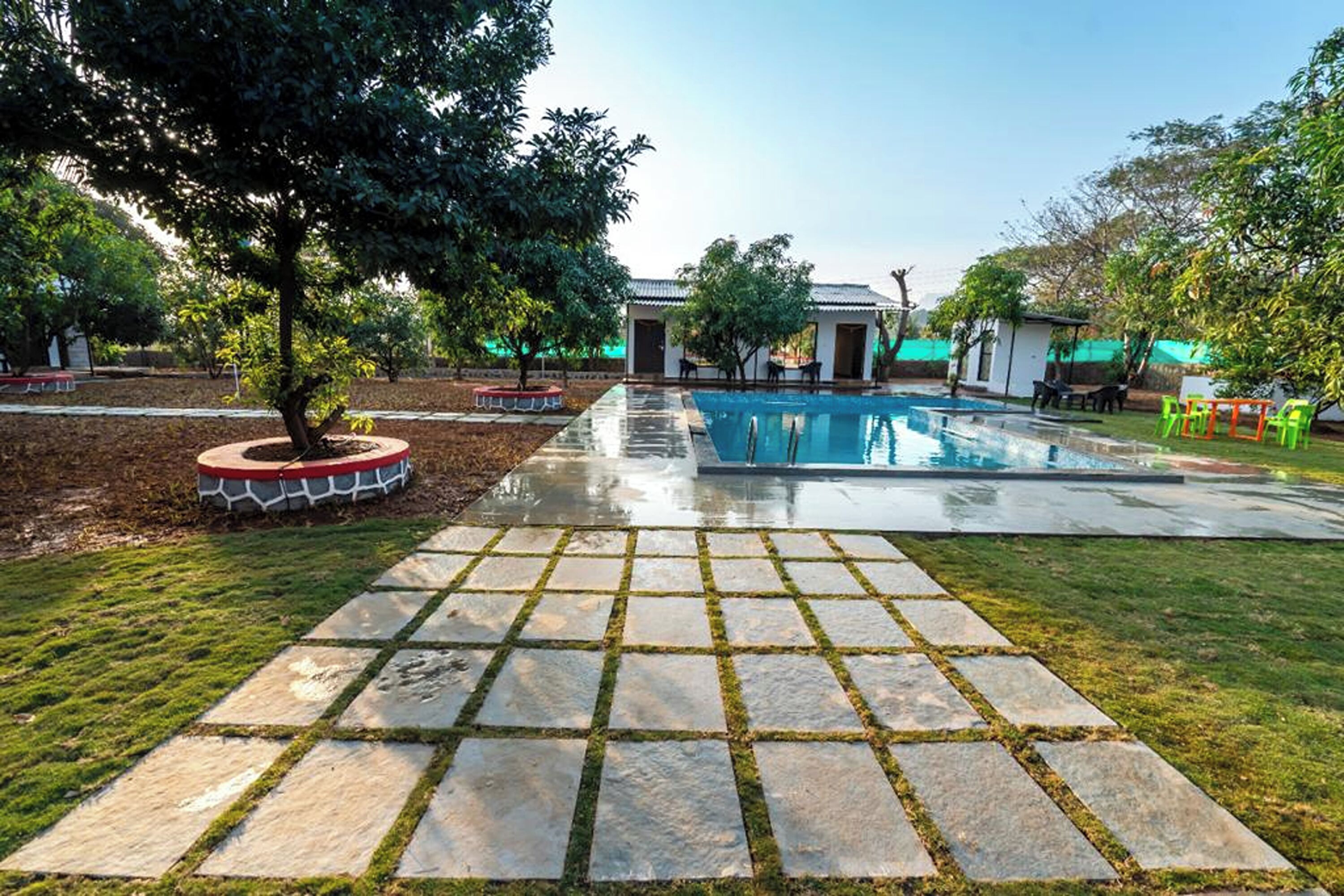 Una piscina con un vialetto in pietra che vi conduce, circondata da erba e alberi.