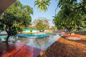 Una piscina rodeada de árboles y un camino con baldosas rojas.
