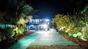 Un sentiero che conduce a un edificio di notte, illuminato da luci e addobbato con palloncini.