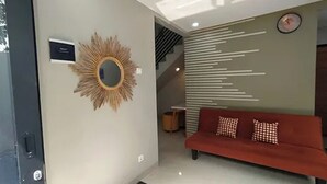 Un interior moderno con un sofá, un espejo decorativo y una pared con líneas horizontales.