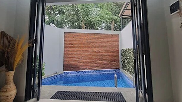 Un interior moderno con vistas a una piscina al aire libre, un muro de ladrillo y una planta en maceta.